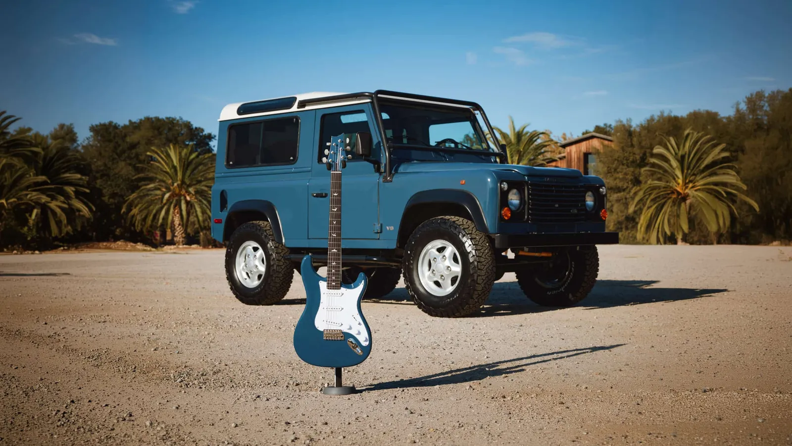 Arles Blue PRS Silver Sky Defender guitar standing in front of an Arles Blue classic Land Rover Defender 90